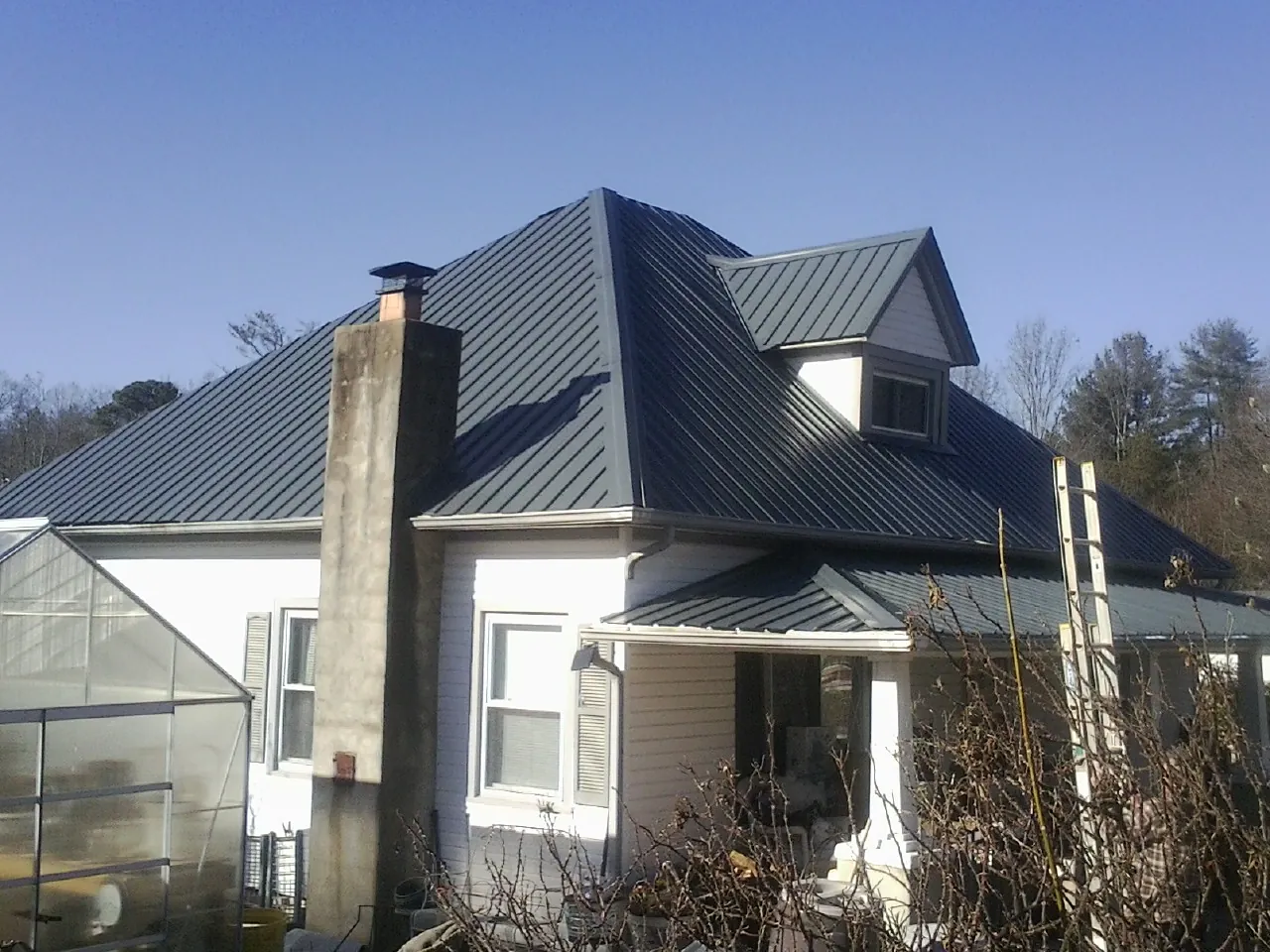 Dark blue standing seam metal roof on a white farmhouse with dormer — Slate & Tile Roof Repair by Roofing Brothers in Silverthorne