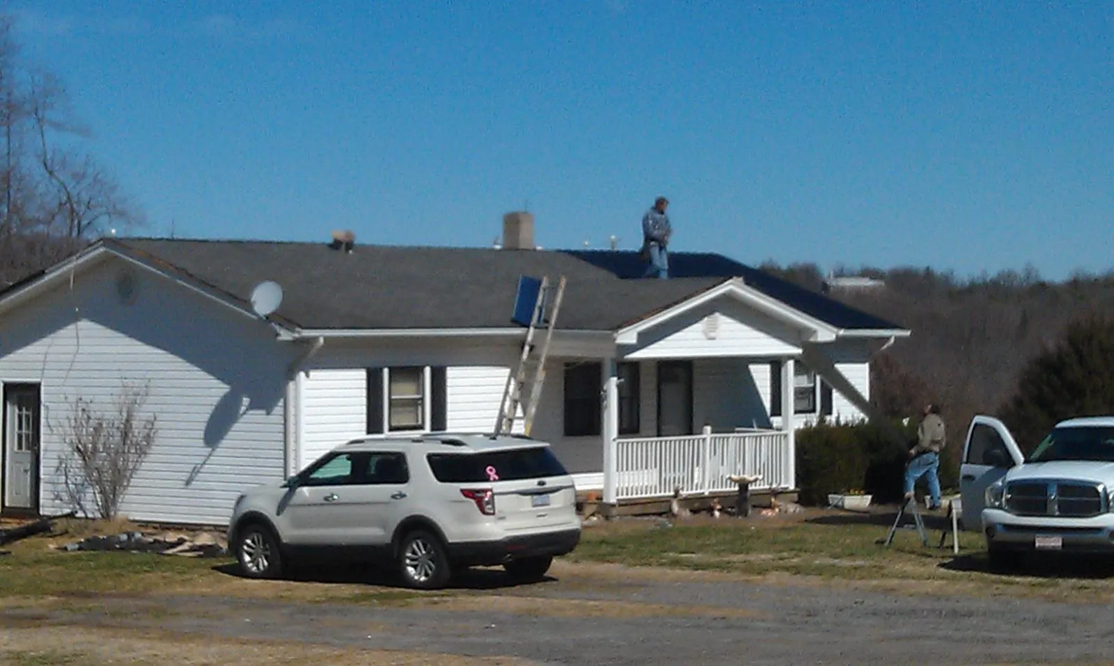 Roofers stripping shingles from a white ranch house roof in Silverthorne
