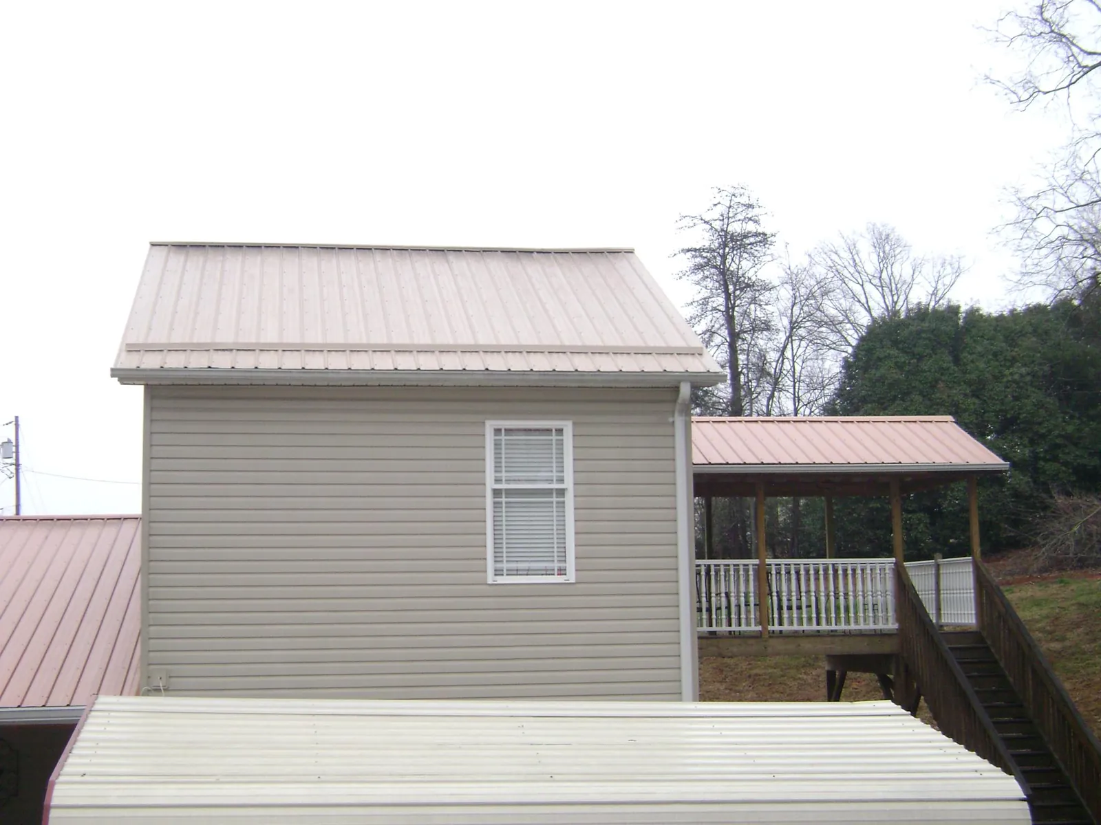 Tan metal roofs on a two story addition and attached porch, from a Roof Replacement job in Silverthorne